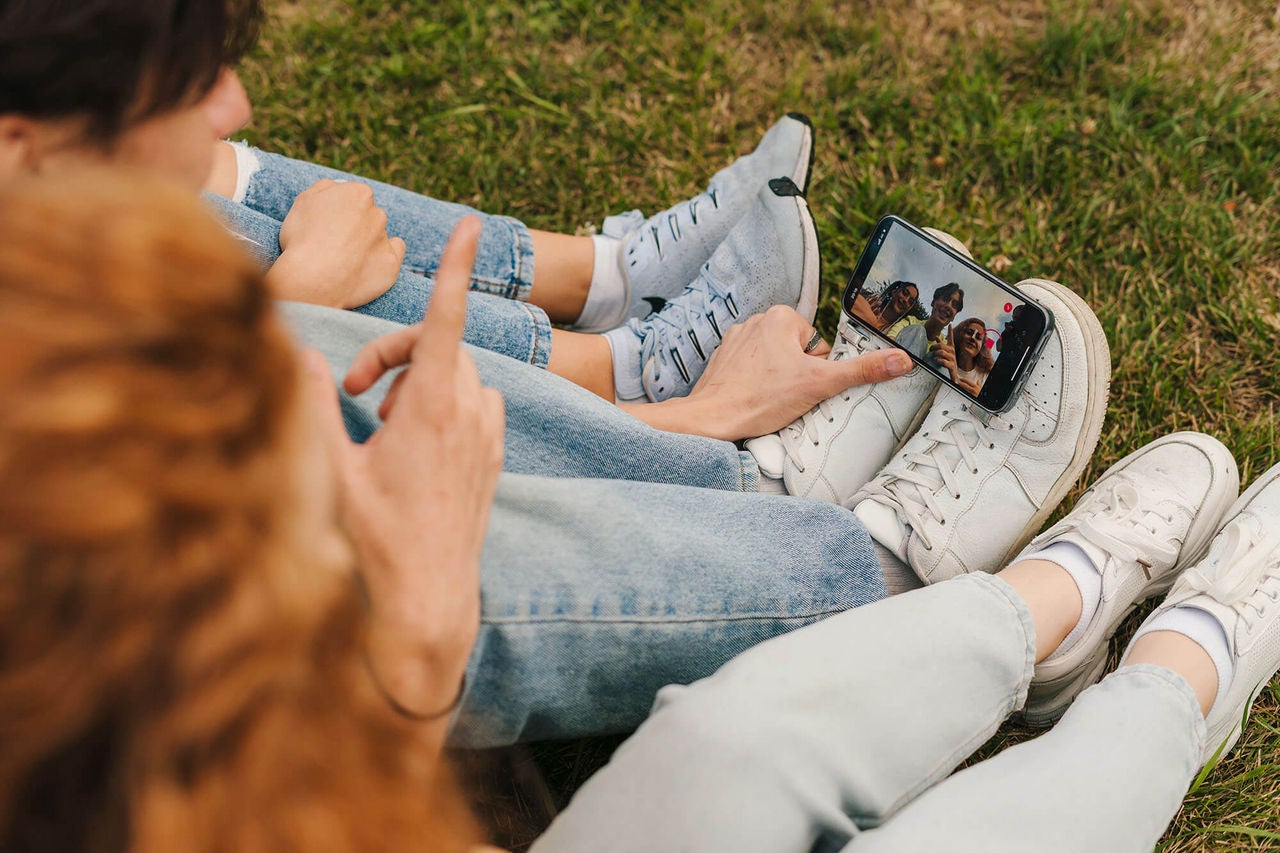 Teenagers sitting on ground using iPhone in Australia