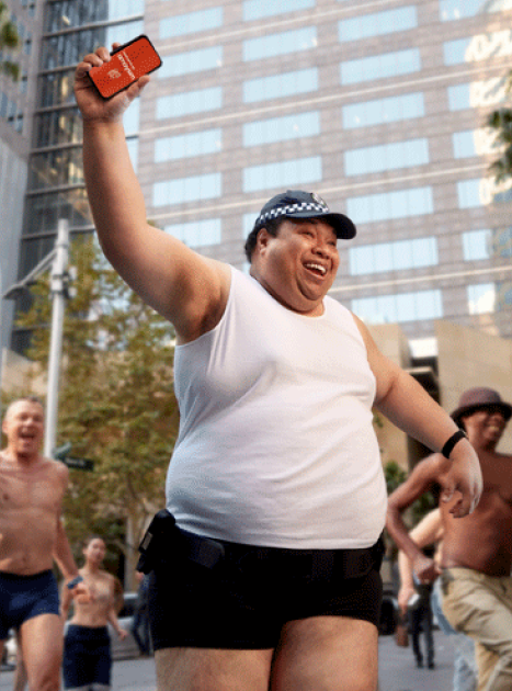 a joyous cop in his singlet running down the street wielding an orange amaysim phone