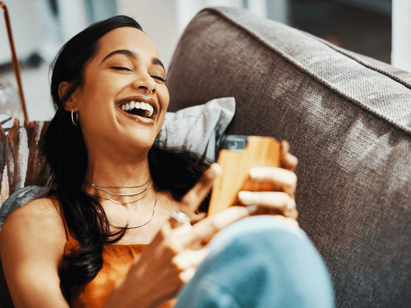 a woman clearly enjoying her new amaysim mobile plan while she reclines on her couch